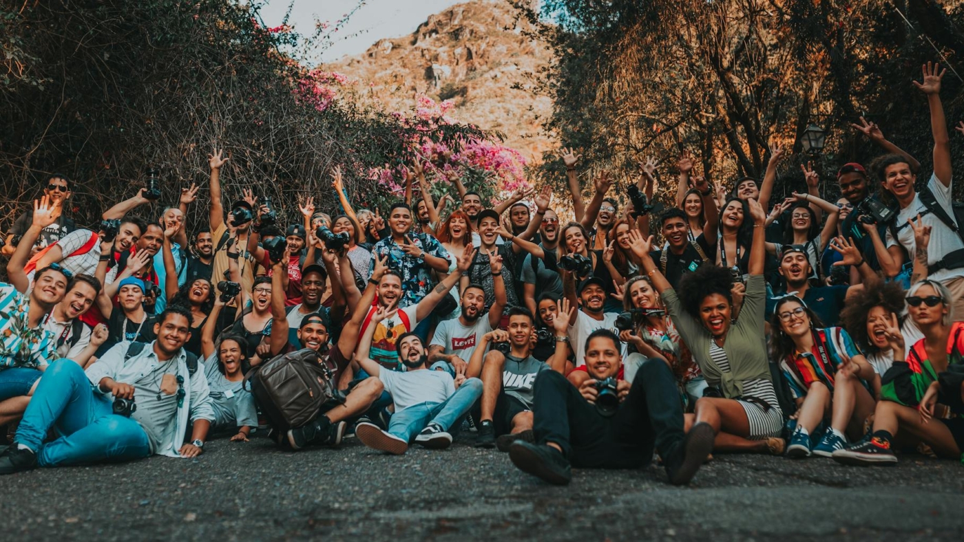 group of diverse cheerful people with raised arms on pavement