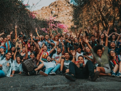 group of diverse cheerful people with raised arms on pavement